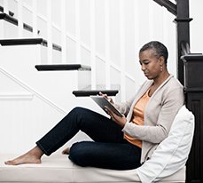 woman sitting on stairs looking at Mira on a tablet